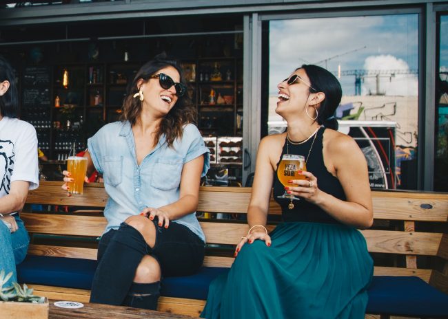 pexels-photo-1267696 two smiling women sitting on wooden bench