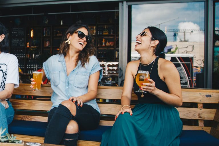 two smiling women sitting on wooden bench
