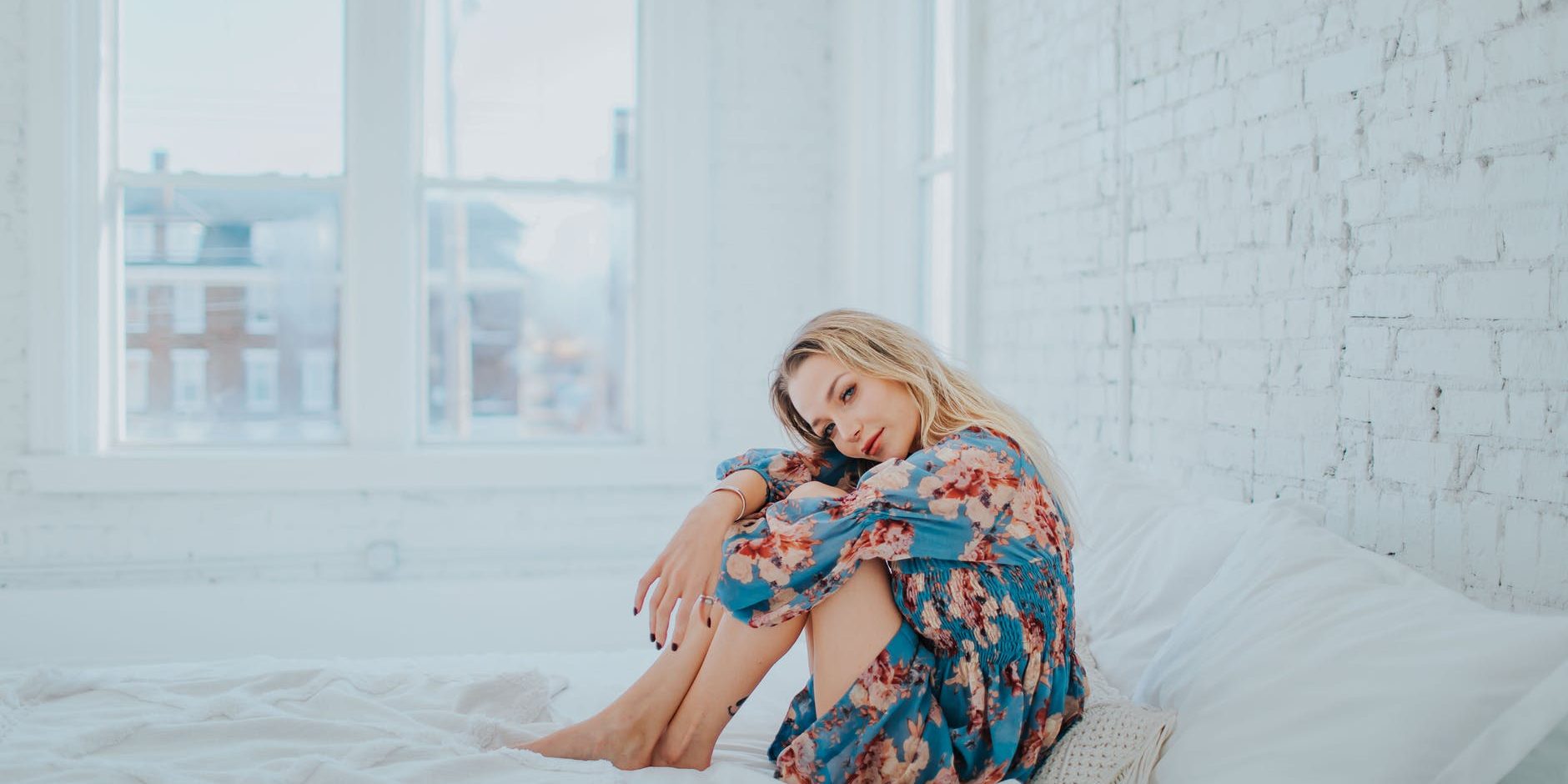 pexels-photo-3586911 woman wearing floral dress while sitting on bed